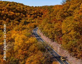 A fall scenic bird's eye view of a yellow car going up a long curvy road in West Salem, Wisconsin.